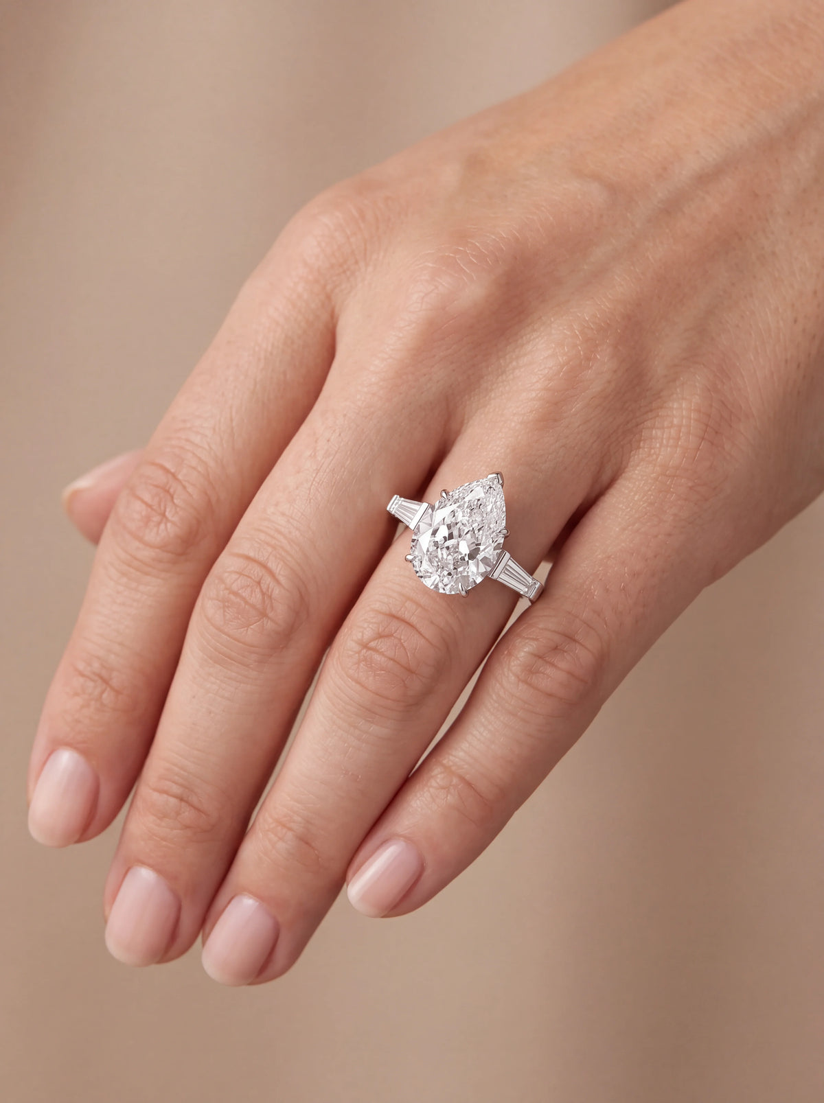 Anel de noivado diamante pera 4ct trilogia baguete em ouro branco visto na mão — 1999